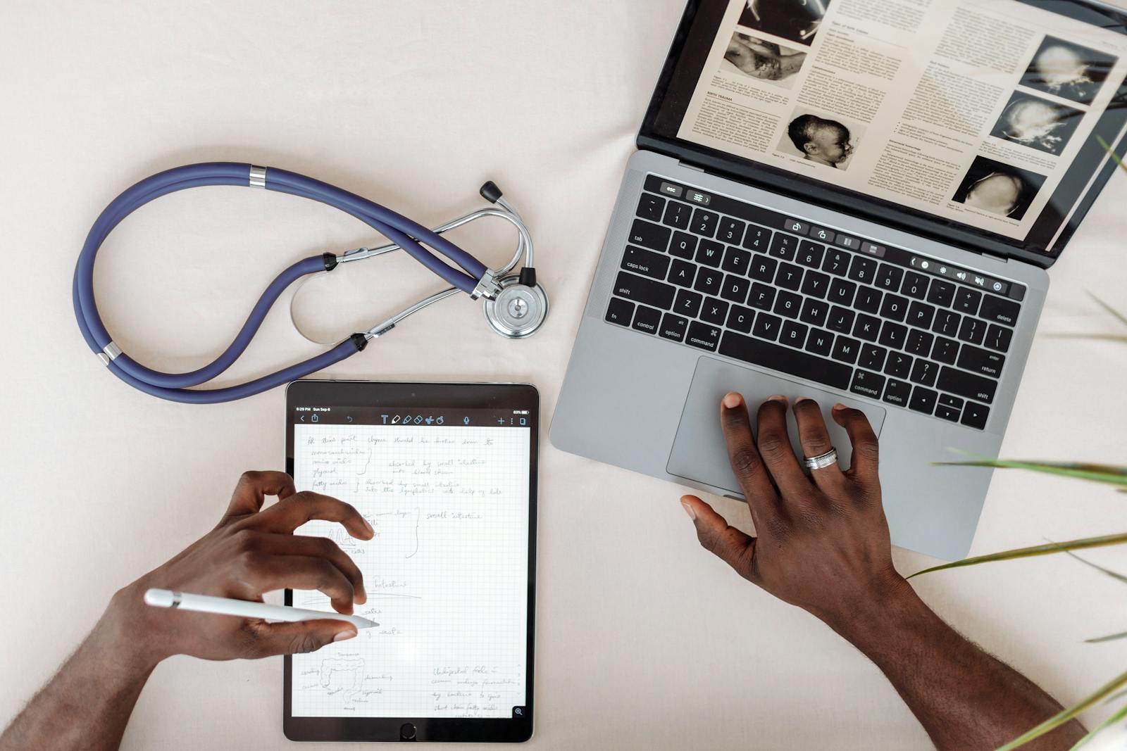 Digital health workspace with laptop, tablet and stethoscope.